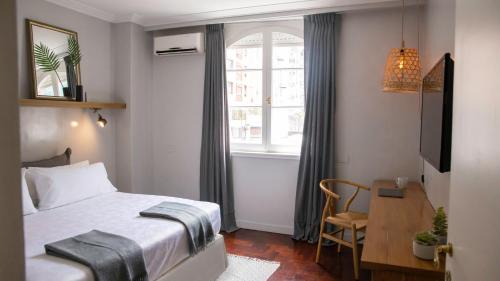 a bedroom with a bed and a desk and a window at Carsson Hotel Downtown Buenos Aires in Buenos Aires
