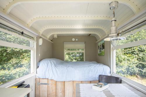 a bedroom in a trailer with a bed and two windows at Pipowagens 'Ot' en 'Sien' in Kuinre