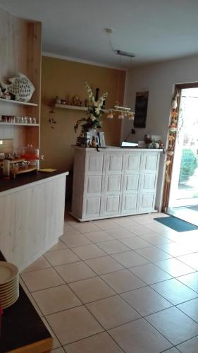 a kitchen with white cabinets and a tile floor at Pension Mien Fründt in Baabe