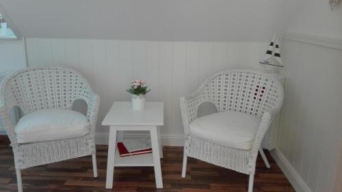 two wicker chairs and a table in a room at Pension Mien Fründt in Baabe