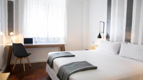 a bedroom with a bed and a desk and a window at Carsson Hotel Downtown Buenos Aires in Buenos Aires