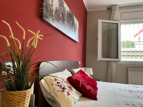 ein Schlafzimmer mit einer roten Wand mit einem Bett und einer Pflanze in der Unterkunft Villa Cambrils Beach in Cambrils