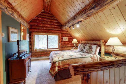 a bedroom in a log cabin with a bed and a television at Bear Hollow Cabin in Tacoma