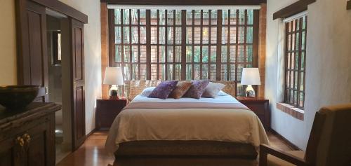 a bedroom with a large bed with two windows at Casa Embrujo Morelia - Boutique in Morelia