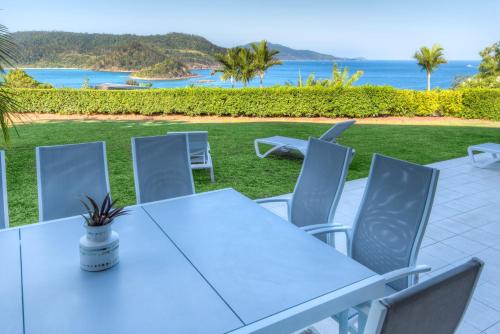 a white table and chairs with a view of the ocean at Bella Vista East 3 Luxury Ocean Views Large Flat Grassed Area And Buggy in Hamilton Island