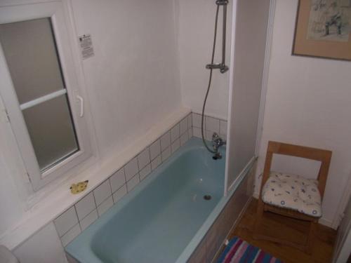La salle de bains est pourvue d'une baignoire bleue avec une chaise. dans l'établissement Quai Peree Apartement, à Saint-Valery-sur-Somme