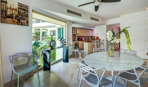 a dining room with a glass table and chairs at Luxurious & Central Condo In Playa Steps From The Beach in Playa del Carmen