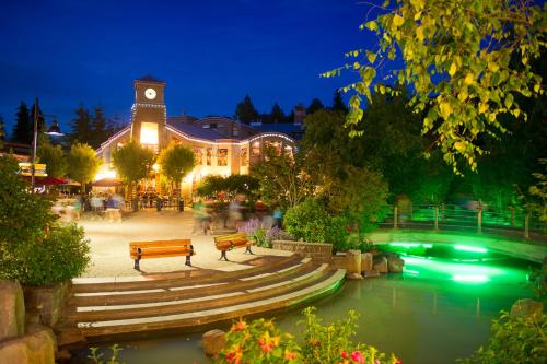 a building with a clock tower and a river with benches at Tyndall Stone Lodge by Whiski Jack in Whistler