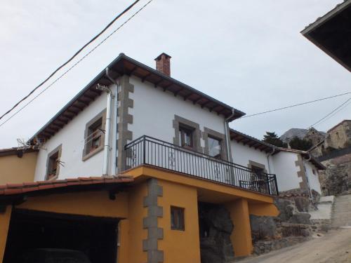 a white and yellow house with a balcony at Casa Rural el Enebral en Potes Picos de Euopa in Colio