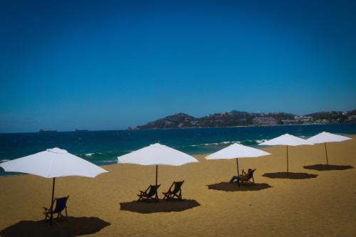 a group of chairs and umbrellas on a beach at Hotel Marbella in Manzanillo
