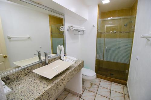 y baño con lavabo, aseo y ducha. en Hotel Marbella en Manzanillo