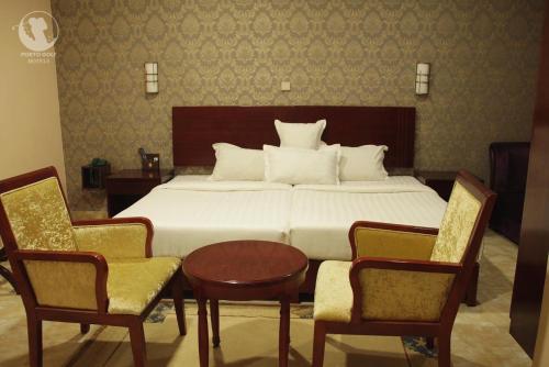 a bedroom with a bed with two chairs and a table at Porto Golf Hotels in Kano