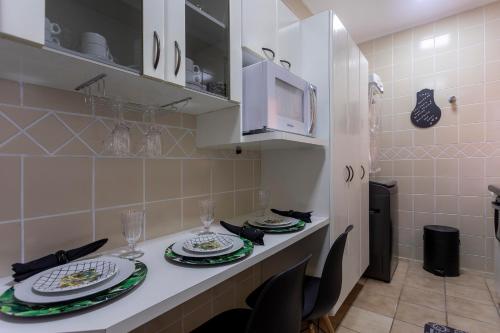 a kitchen with a table with plates and glasses on it at APÊ 5 ESTRELAS CENTRAL-FREE VAGA&NETFLIX in Ribeirão Preto