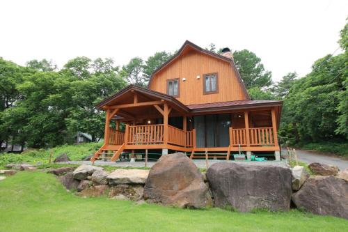 Cottage All Resort Service / Vacation STAY 8450 في Inawashiro: منزل خشبي كبير أمامه صخور كبيرة