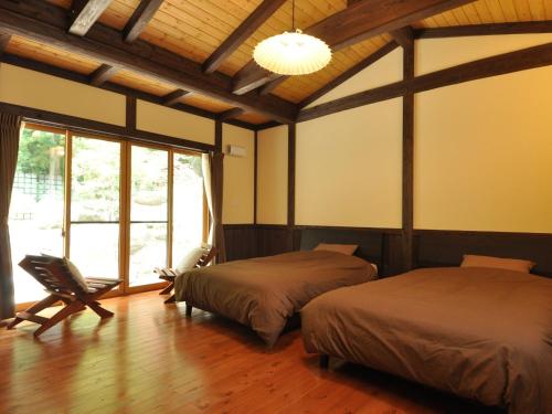 1 dormitorio con 2 camas, silla y ventana en Cottage All Resort Service / Vacation STAY 8448, en Inawashiro