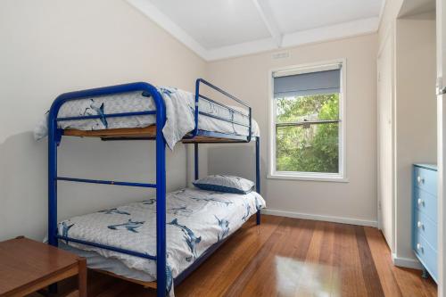 a bedroom with two bunk beds and a table at Blairgowrie Beach Baby in Blairgowrie