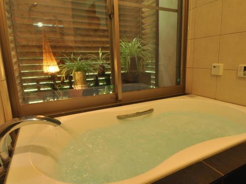 eine Badewanne mit Fenster und einige Pflanzen in der Unterkunft Cottage All Resort Service / Vacation STAY 8445 in Inawashiro