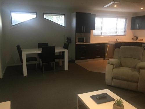 a living room with a couch and a table and a kitchen at Macquarie Barracks Motor Inn in Port Macquarie