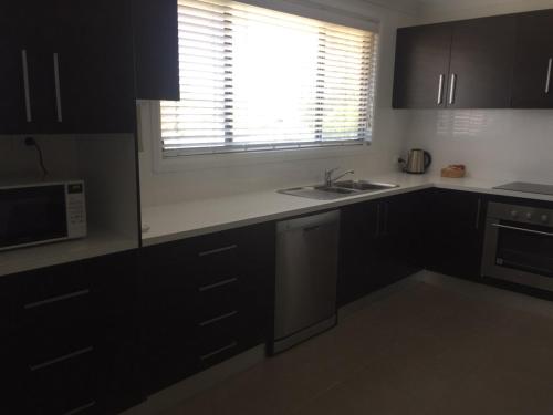 a kitchen with black cabinets and a sink and a window at Macquarie Barracks Motor Inn in Port Macquarie
