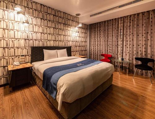 um quarto com uma cama grande e uma cadeira vermelha em 伊都旅店 Motel em Dacun