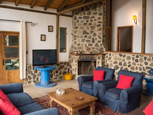 a living room with blue couches and a stone fireplace at Casa de Lujo La Campana in Olmué