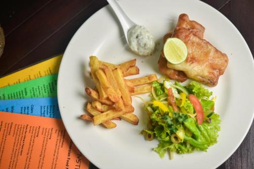 ein Teller mit Essen mit Pommes Frites und einem Stück Fleisch in der Unterkunft Bali Mystique Hotel & Apartment in Seminyak