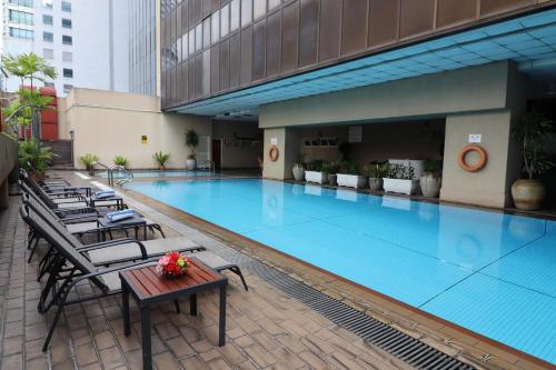 a large swimming pool with chairs and a table at Hotel Grand Continental Kuala Lumpur in Kuala Lumpur