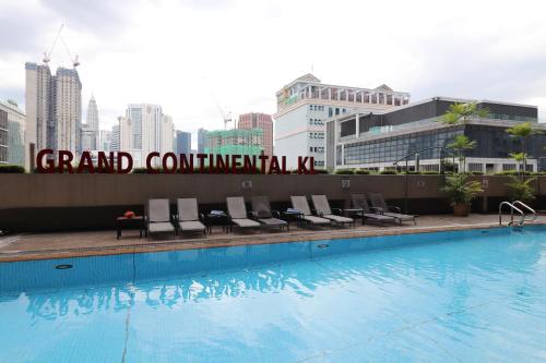 a pool with chairs and a sign on the side of a building at Hotel Grand Continental Kuala Lumpur in Kuala Lumpur