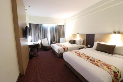 a hotel room with two beds and a desk at Hotel Grand Continental Kuala Lumpur in Kuala Lumpur