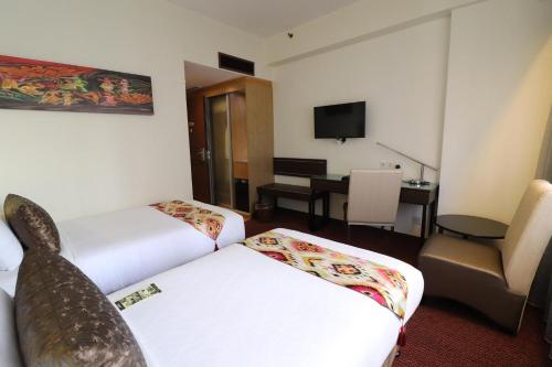 a hotel room with two beds and a desk at Hotel Grand Continental Kuala Lumpur in Kuala Lumpur