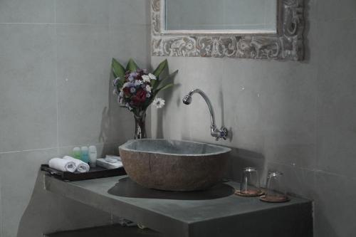 a bathroom with a bowl sink and a vase of flowers at Nyang - Nyang Bungalow Uluwatu in Uluwatu