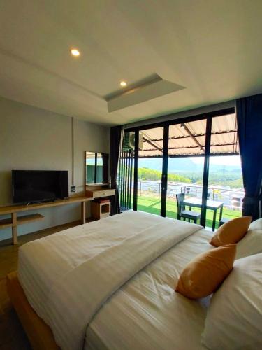 a bedroom with a large white bed with a large window at Cheow Lan Easy Home in Ban Tha Khun