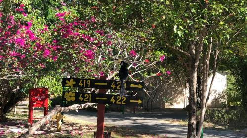 a sign in front of a tree with pink flowers at Frangipani Langkawi Resort in Pantai Cenang