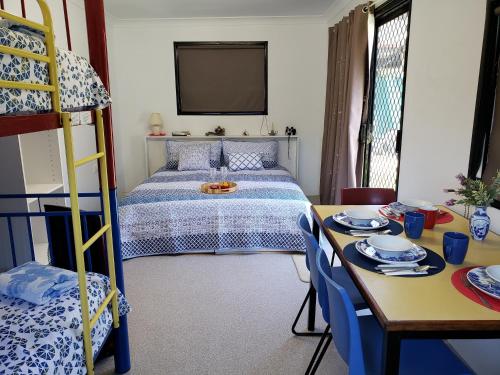 1 dormitorio con cama, mesa y escritorio en Christmas Creek Café & Cabins en Lamington