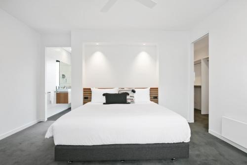 een witte slaapkamer met een groot bed met witte muren bij Apollo Bay Beach House in Apollo Bay