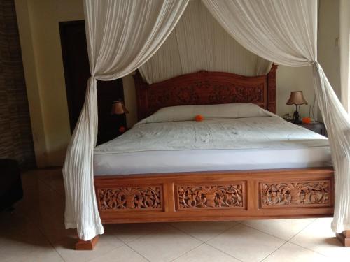 um quarto com uma cama de dossel e cortinas brancas em Dedik House em Ubud