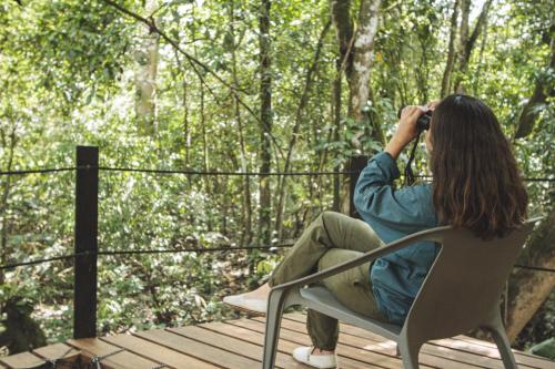 a woman sitting in a chair taking a picture of the woods at La Manigua Lodge in La Macarena
