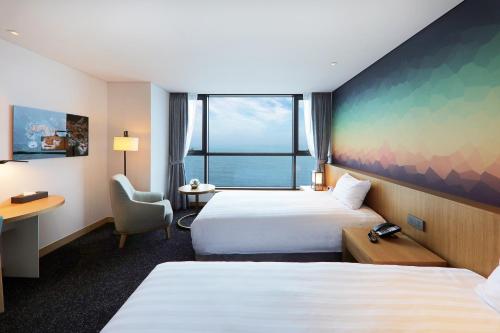 a hotel room with two beds and a window at Mercure Ambassador Ulsan in Ulsan