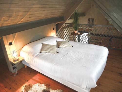 Flines-lès-MortagneにあるLa cabane du chasseurの白いベッド(枕2つ付)が備わる客室です。