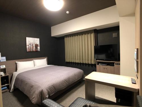 a bedroom with a bed and a flat screen tv at Hotel Route-Inn Shinano Omachi Ekimae in Omachi