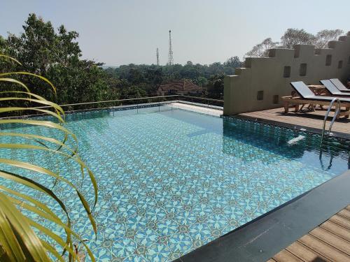 a large swimming pool next to a wooden deck at 3102bce - A Vedic Resort in Vagator