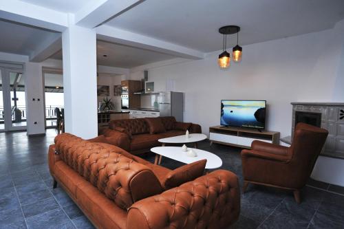 a living room with brown leather furniture and a tv at Lagadin Lakeview Apartment in Ohrid