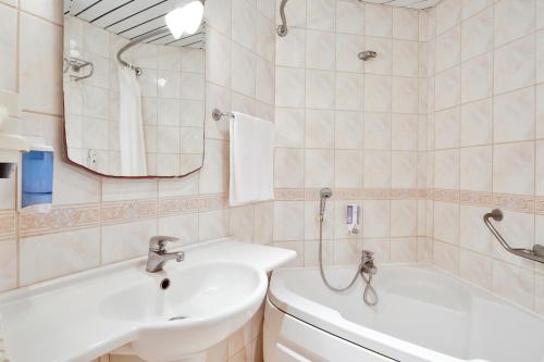 a bathroom with a sink and a tub and a mirror at Costa 3S Beach Hotel-All Inclusive in Bodrum City