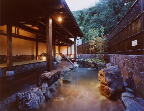 a building with a pool of water with rocks at Aridagawa Onsen Hotel Sunshine in Arida