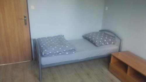 a small bed in a room with two pillows on it at Hostel Lisięcice in Lisiecice