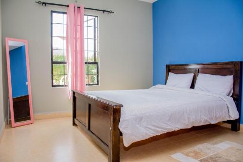 1 dormitorio con 1 cama grande y paredes azules en Beautiful and Homely, en Eldoret