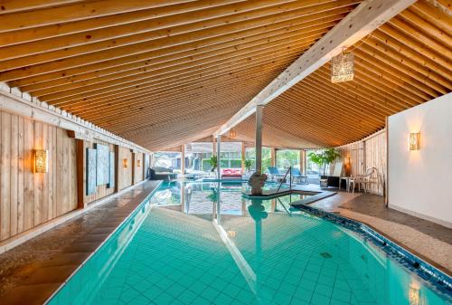 an indoor swimming pool with a wooden ceiling at Chalet Hotel Adler AG in Kandersteg
