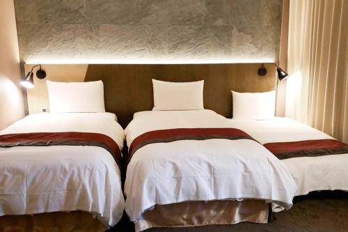 two beds in a hotel room with white sheets at Green World NanGang in Taipei