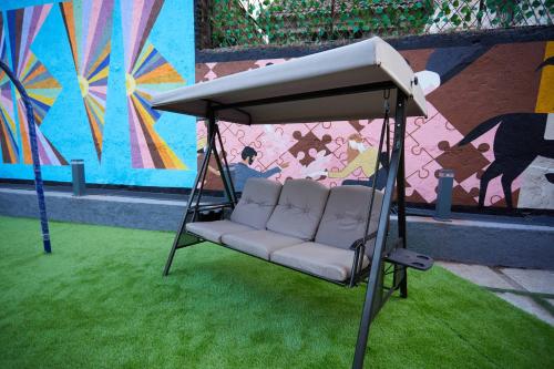 a swing seat in front of a wall with a mural at Aureole Mrida - A Boutique Hotel in Lonavala