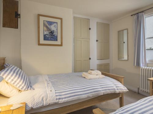 Schlafzimmer mit einem Bett mit blauen und weißen Streifen in der Unterkunft Pixie Cottage in Dartmouth